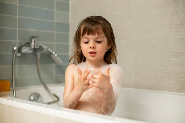 Cute little girl playing with bath foam taking a bath Cute little girl playing with bath foam while taking a bath girls bath stock pictures, royalty-free photos & images