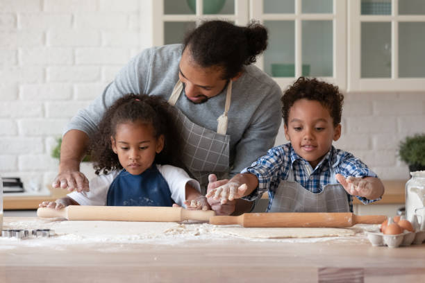 istock Caring African American father teaching kids rolling out dough 1718704603