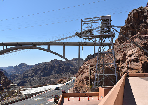 The Hoover Dam is an iconic hydroelectric power plant located in Clark County, Nevada. It stands as a remarkable feat of industrial construction set against a backdrop of clear blue skies and majestic mountains.