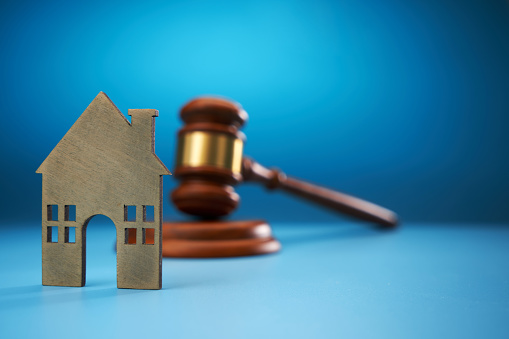 gavel hammer and model house against blue background