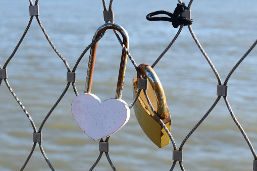 A heart-shaped love padlock in New York, symbolizing love and commitment, hangs on a bridge against a romantic Valentine's Day background.