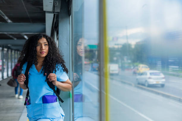 afro medical woman is dressed in her medical uniform on the streets of bogota on her way to work - color image bus discussion expertise imagens e fotografias de stock