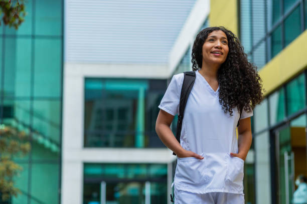 afro medical woman is dressed in her medical uniform on the streets of bogota on her way to work - color image bus discussion expertise imagens e fotografias de stock