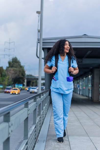 afro medical woman is dressed in her medical uniform on the streets of bogota on her way to work - color image bus discussion expertise imagens e fotografias de stock