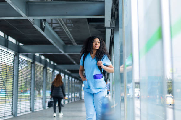 afro medical woman is dressed in her medical uniform on the streets of bogota on her way to work - color image bus discussion expertise imagens e fotografias de stock