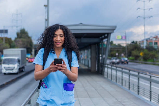 afro medical woman is dressed in her medical uniform on the streets of bogota on her way to work - color image bus discussion expertise imagens e fotografias de stock