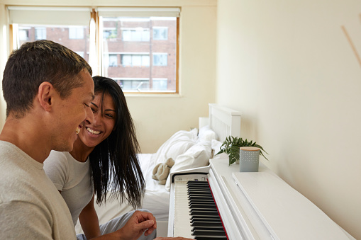 Married couple paying together a piano on their room