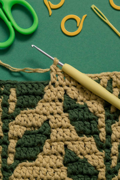 istock Yellow green crochet fabric with foliage pattern and crochet tools on a green background. 1718760829