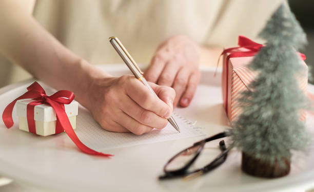 istock A person writing a greeting card on the table next to a small red gift box 1718769025