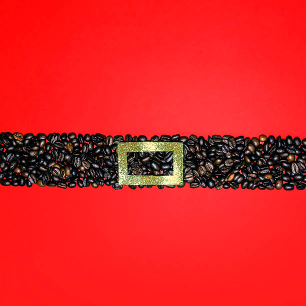 Christmas composition. Santa belt made of coffee beans and gold ribbon  against red background. Flat lay, top view, copy space. New Year sale card. Coffee lovers.