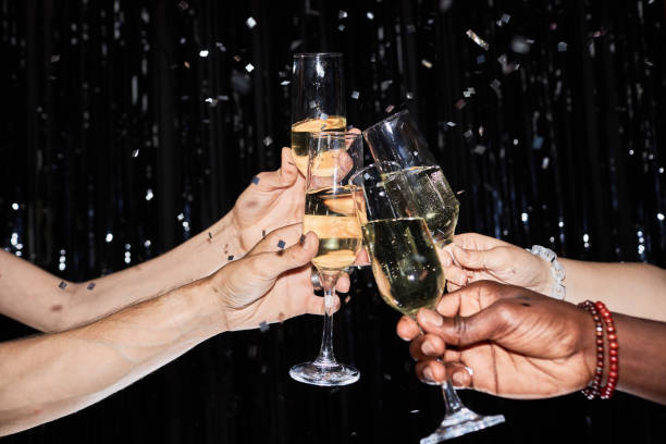 Group of friends toasting drink glasses together at nye Party