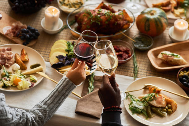 close up of two people toasting celebrating thanksgiving with friends and family - wine dinner party drinking toast imagens e fotografias de stock