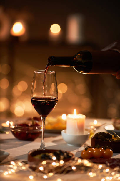 gros plan de vin rouge versé dans un verre à une table festive - champagne flute champagne black wineglass photos et images de collection