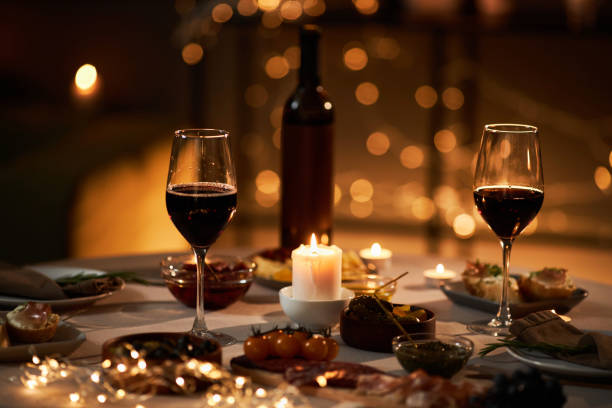 istock Two wine glasses on dinner table with Christmas lights and candles 1718782654