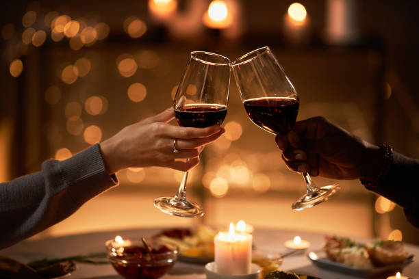 저녁 식탁에서 와인잔을 부딪히는 두 사람의 클로즈업 - christmas dinner candle fire 뉴스 사진 이미지