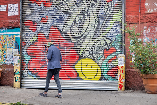 West 27th Street, Manhattan, New York, USA - August 17th 2023: Person passing a colorful door to a professional garage