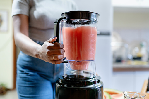 Cropped shot of a woman preparing watermelon juice in an electric blender mixer machine on home kitchen