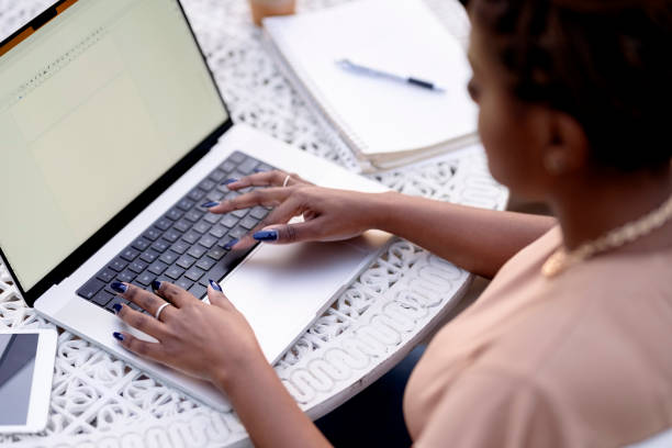 Woman working on a laptop sitting at table in backyard