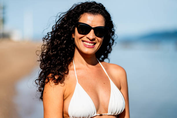 istock Smiling woman in a bikini standing on a sandy beach in summer 1718802315