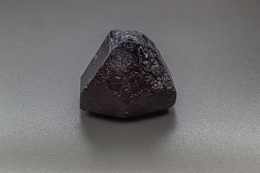 Macro focused black tourmaline schrol crystal isolated on gray background
