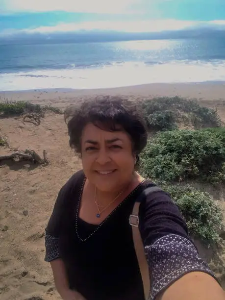 Mature hispanic woman enjoying the sun and sea on California coast road trip.