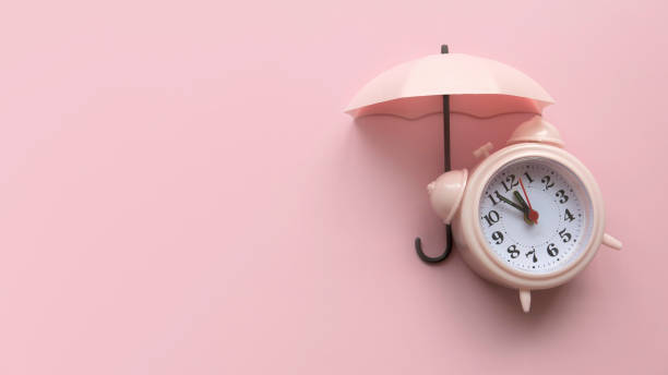 istock Clock under an umbrella. Concept of protection time. Pink background with copy space. 1718836026