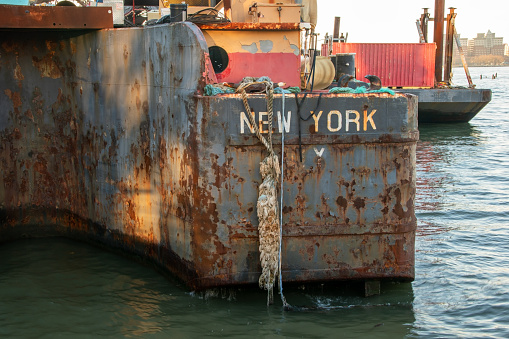 Coils of cable and gas cylinders are scattered across the weathered deck of an old, rusty barge, creating a rugged industrial scene.