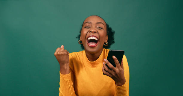 istock Young Black woman reads text message shocked excited, green studio background 1718872629