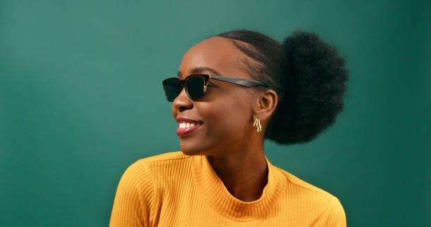 Beautiful young woman profile view with sunglasses, green studio background stock photo
