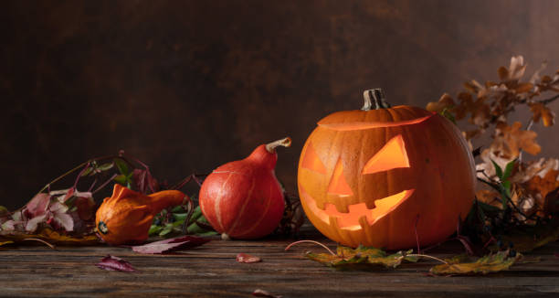 istock Halloween pumpkin head jack lantern with dried-up leaves. 1718894621
