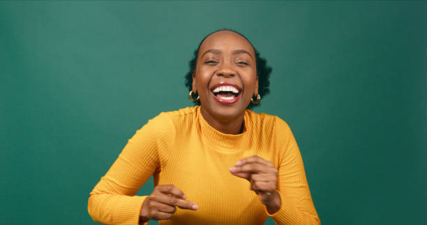 Happy young woman dancing, having fun, green studio background stock photo