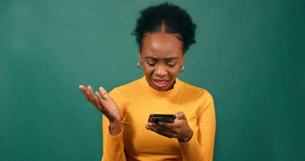 istock Young woman reads text message, upset and confused, green studio background 1718896746