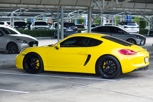 Yellow Porsche Cayman in parking lot at Home Pro market at Pradit Manutham Rd in Bangkok