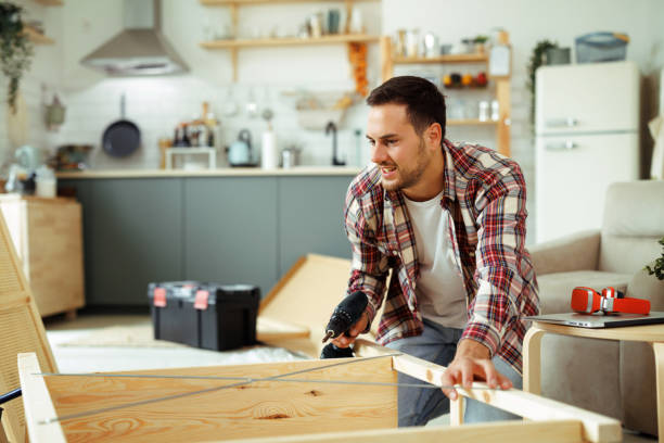 istock Young casually clothed man assembling wooden shelf with electric power drill 1718901688