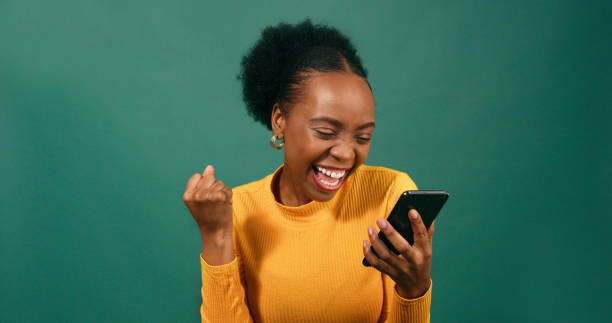 istock Young Black woman reads text message shocked excited, green studio background 1718905037