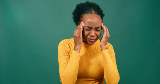 istock Young Black woman rubs temples, headache, green studio background 1718906681