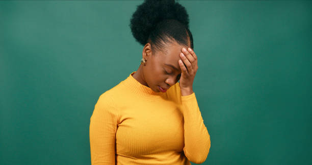 istock Young Black woman covers face with hand, face palm, green studio background 1718912616