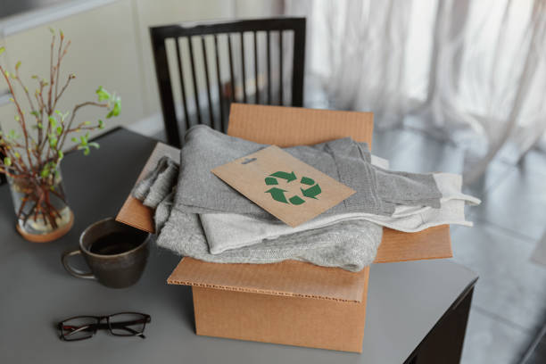 Box with used wardrobe for reuse and card with circular economy logo. Reusing, recycling materials and reducing waste in fashion, second hand apparel idea. Circular fashion, zero waste concept