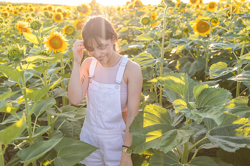 A beautiful smile in a field of sunflowers in the summer rays of the sun.