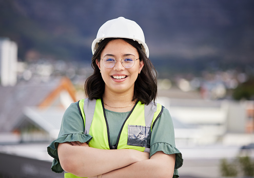 Engineering, crossed arms and portrait of a female construction worker on a building rooftop. Confidence, industry and woman industrial manager for maintenance, renovation or inspection in the city.