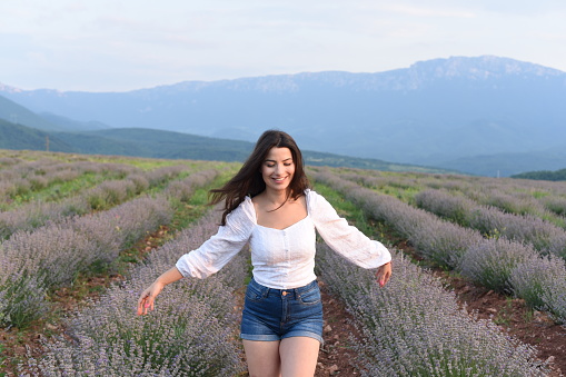 A girl with her arms outstretched enjoys the beauty of nature and the fresh, fragrant air in a field of lavender.
