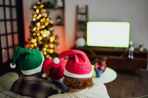 Rear view of a family watching television on Christmas time at home - Green screen mock up