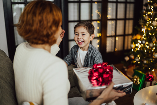 Mother receiving Christmas gifts from her son at the home