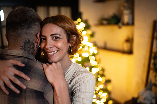 Portrait of a mid adult woman dancing or embracing with husband Christmas time at the home