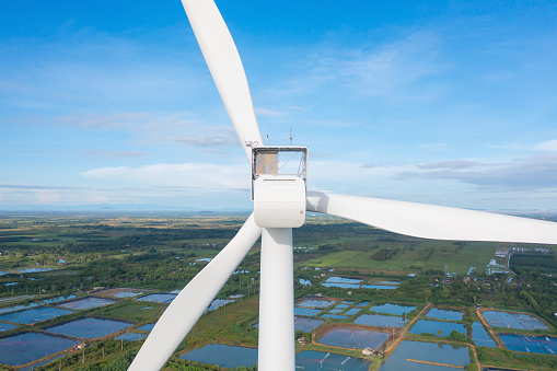 Aerial view of wind turbines or windmills farm field and sea shore beach in industry factory. water power, sustainable green clean energy, and environment concept. Nature innovation.