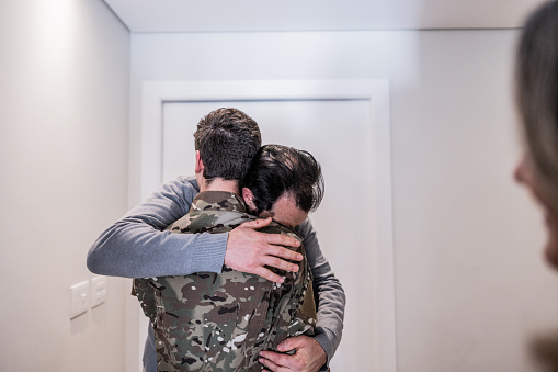 Mature man embracing his soldier son that returned home