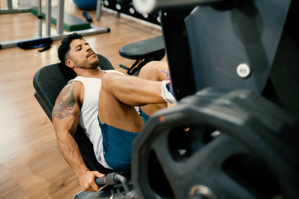 istock Muscular man doing thigh workout on exercise machine in gym 1719026699
