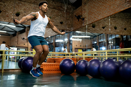 Fit young man exercising with jumping rope at the fitness gym