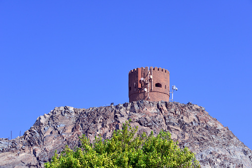 Riyam, Wilayat Muttrah, Muscat, Oman: old cylindrical coastal defense tower at the harbor entrance, probably of Portuguese origin, still equipped with 17th century cannons, but covered in mobile phone network antennas - perched on a rocky hill just south of the Muscat marine tower - Al-Bahri road, the corniche.