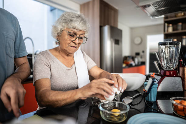 istock Senior woman breaking eggs at home 1719045037
